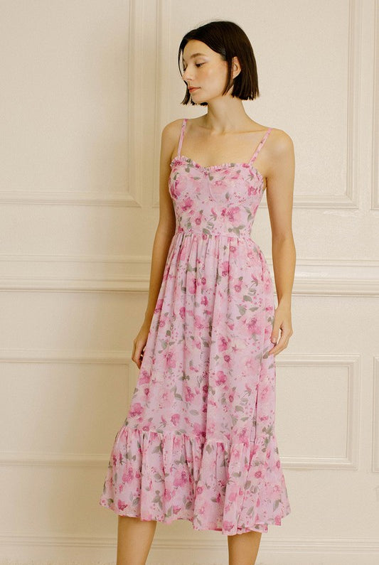 Woman wearing a pink floral dress against a neutral wall.