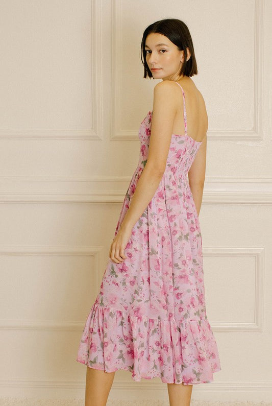 Back view of a woman wearing a pink floral dress against a neutral wall.