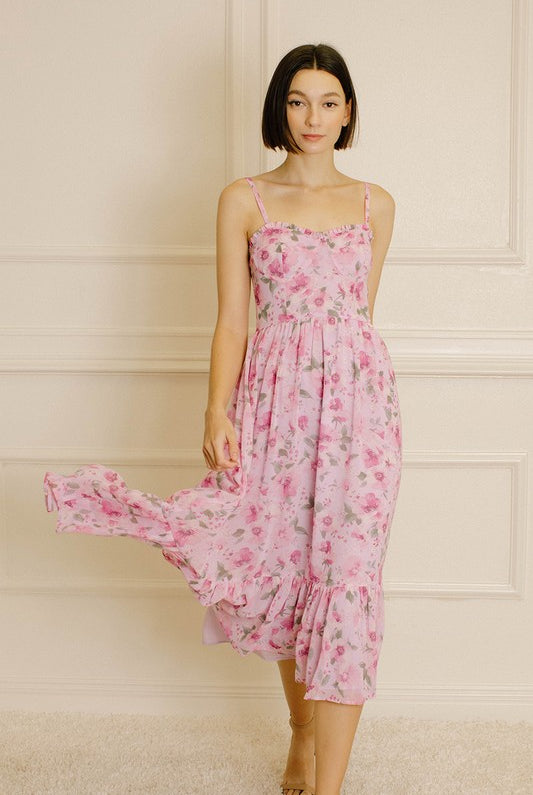 Woman wearing a pink floral dress against a neutral wall.