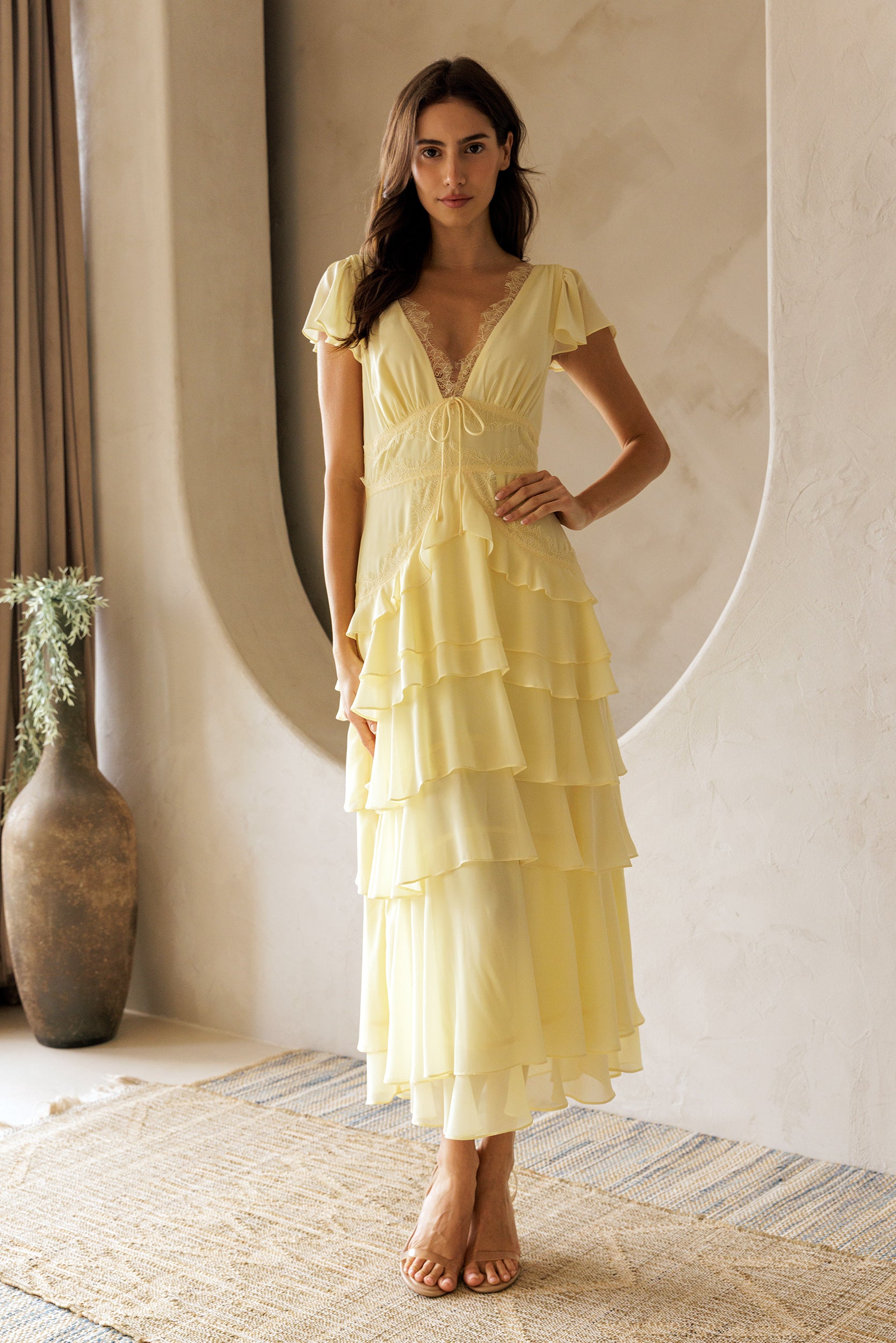 Woman wearing a yellow dress standing in a room with a neutral color palette.