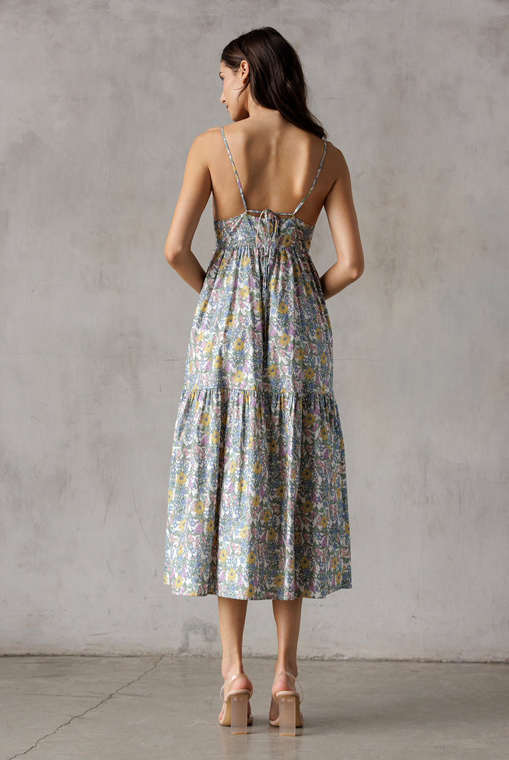 Woman wearing a floral dress and brown high-heels with a neutral background