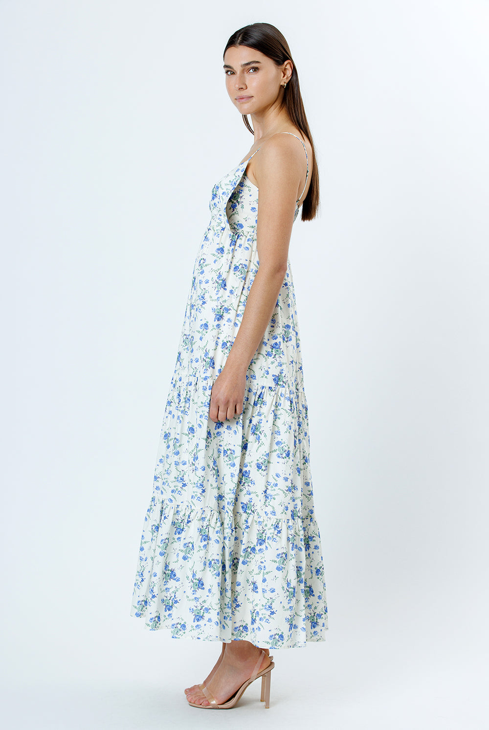 Side view of a woman wearing a floral dress with blue flowers on a white background