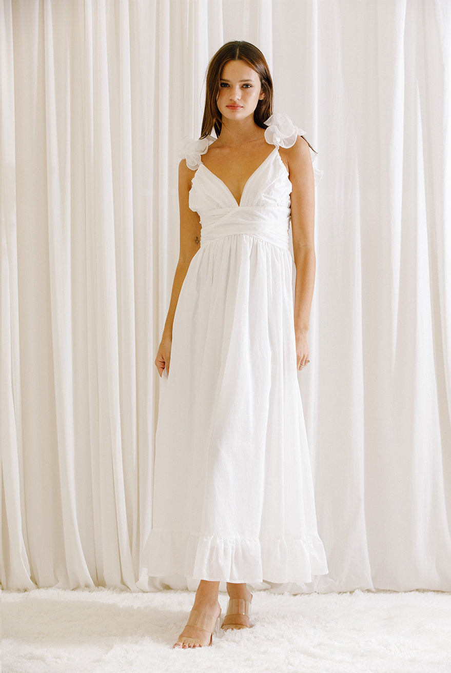 Woman wearing a white dress standing in front of white curtains