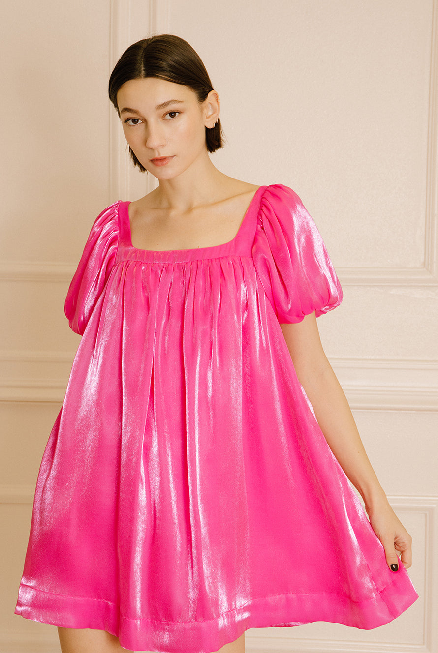 Woman wearing a pink nightgown against a beige wall