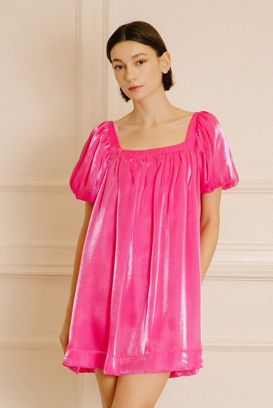 Woman wearing a pink nightgown silhouette against a beige wall