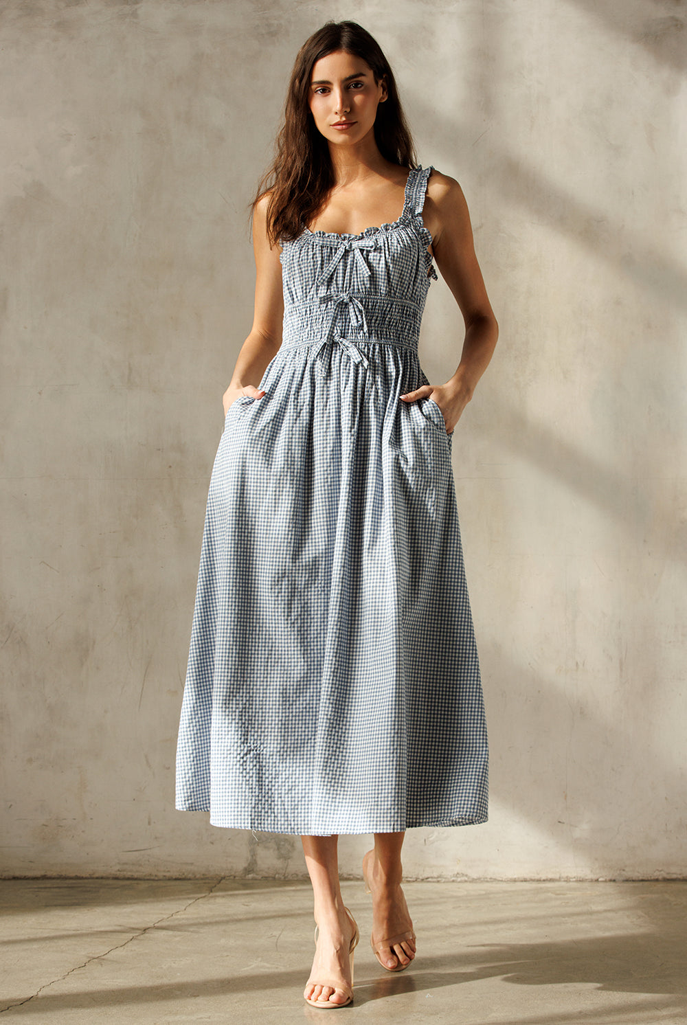 Woman wearing a blue checkered dress against a neutral background