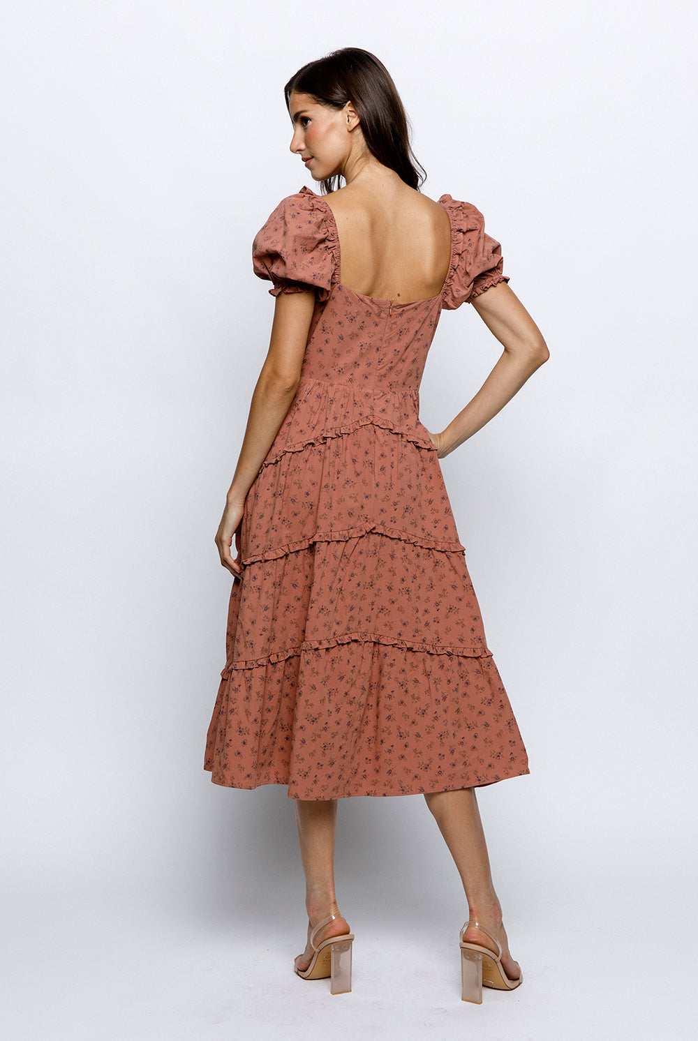 Back view of a woman wearing a mauve floral dress on a white background