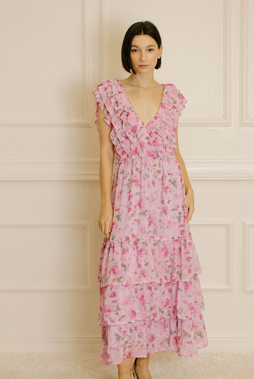 Woman wearing a pink floral dress against a neutral wall.