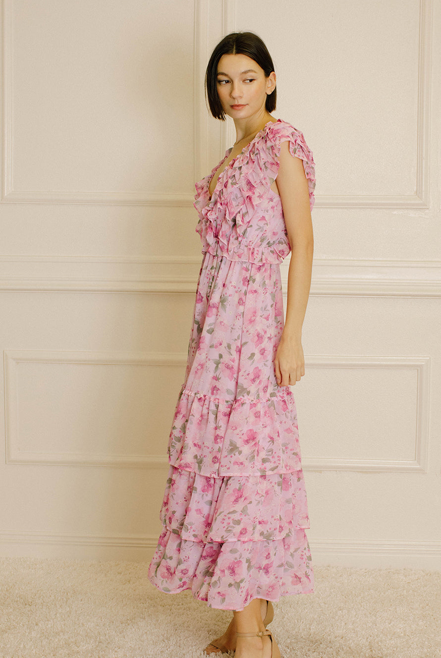 Side view of a woman wearing a pink floral dress against a neutral wall.