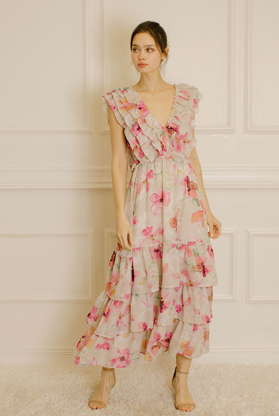 Woman wearing a grey and pink floral dress against a white paneled wall