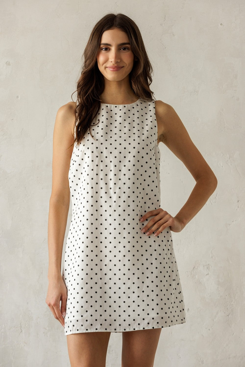Woman wearing a polka dot dress against a plain background