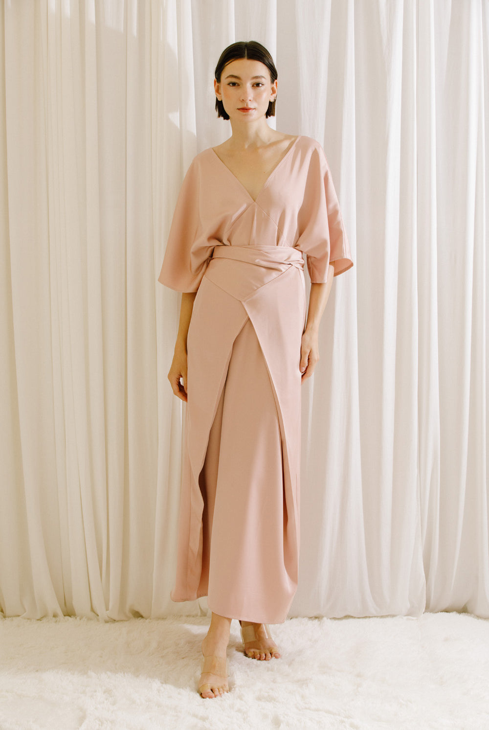 Front view of a woman wearing a pink V-neck maxi dress with fluid drape
