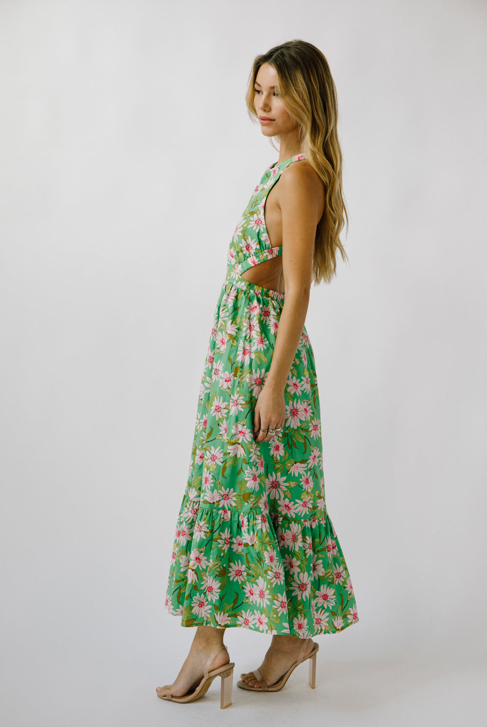 Side view of a woman wearing a green floral dress on a white background