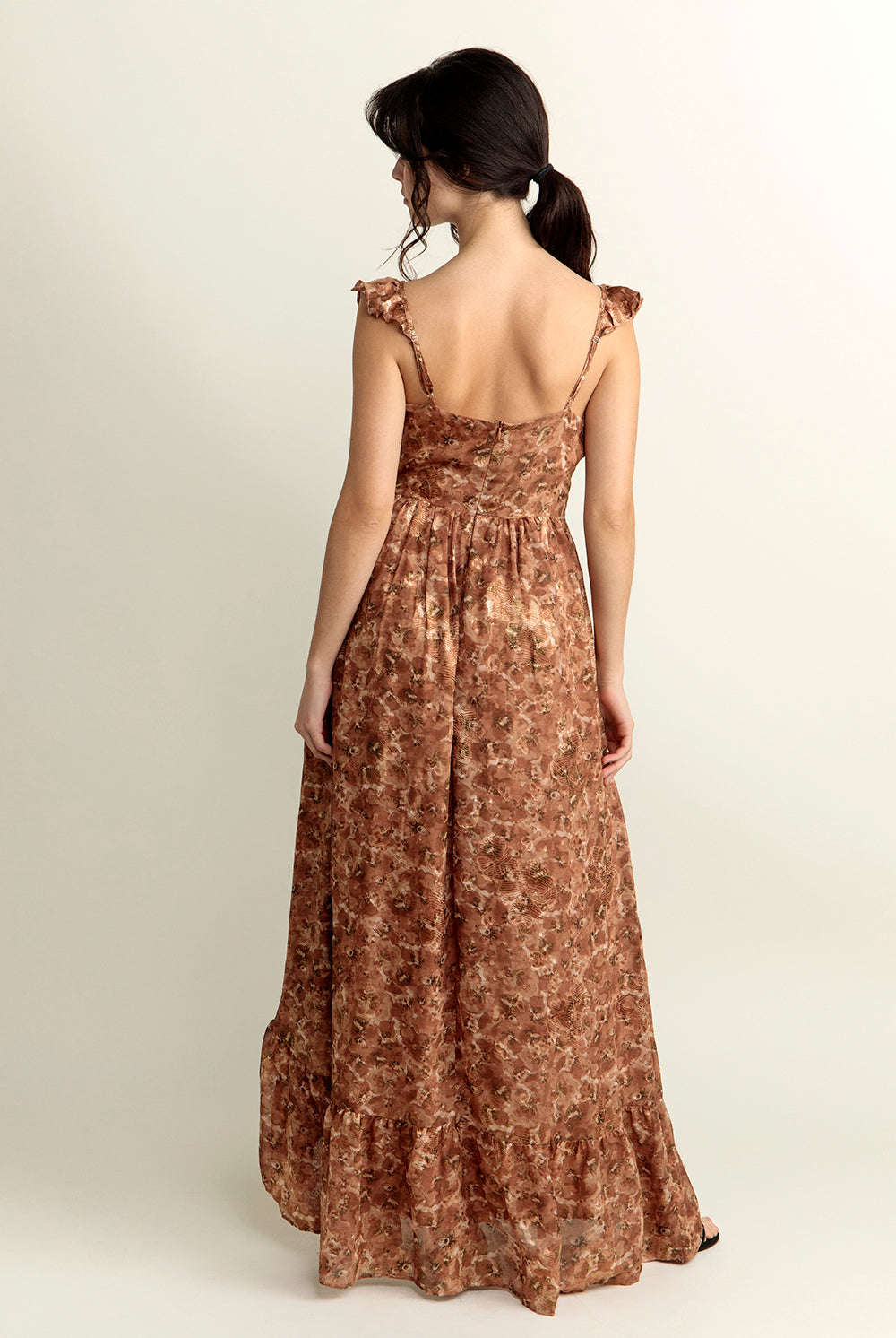 Back view of a woman wearing a brown floral dress on a white background