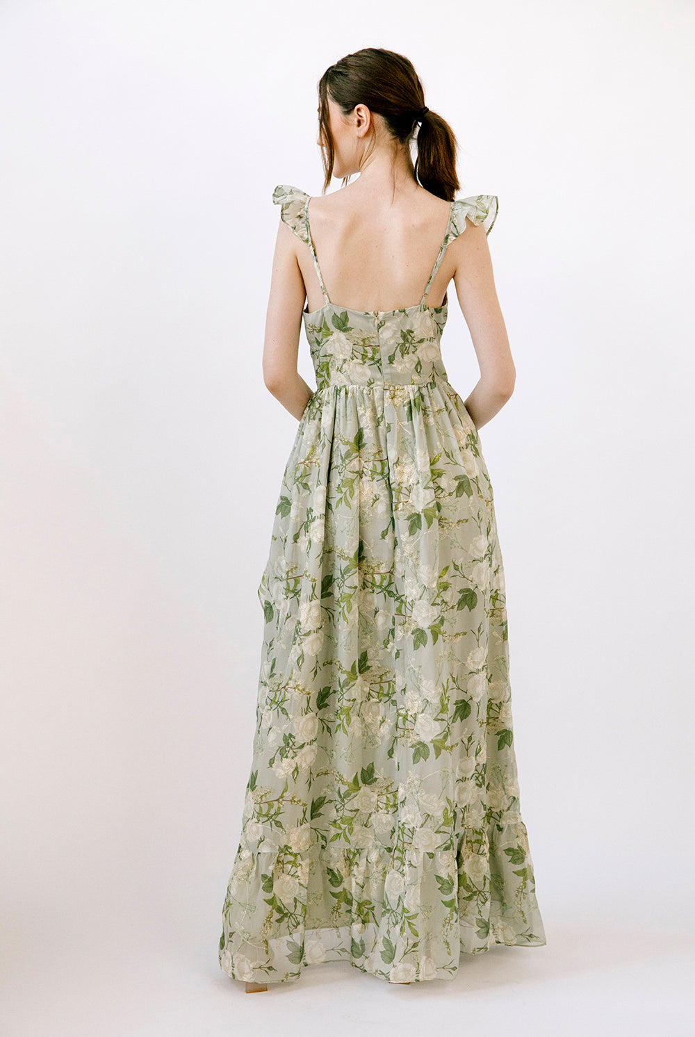 Back view of a woman wearing a floral dress with a white background
