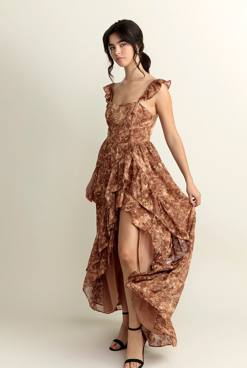 Woman wearing a brown floral dress with a slit on a white background