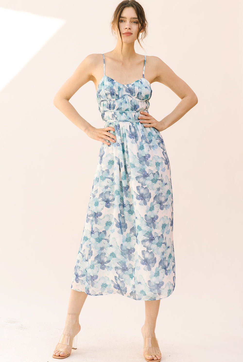 Woman wearing a blue watercolor floral midi dress on a plain background