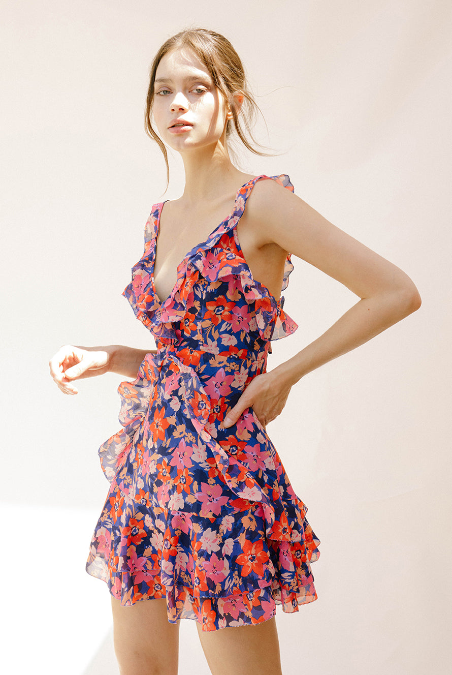 Side view of a woman wearing a colorful floral dress against a plain background