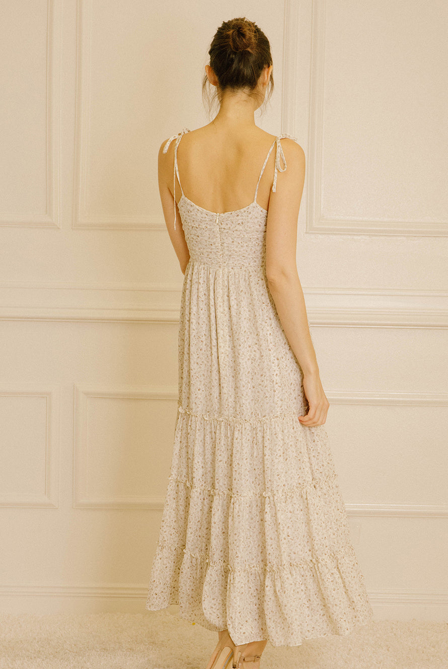 Back view of a woman wearing a grey floral dress against a beige paneled wall