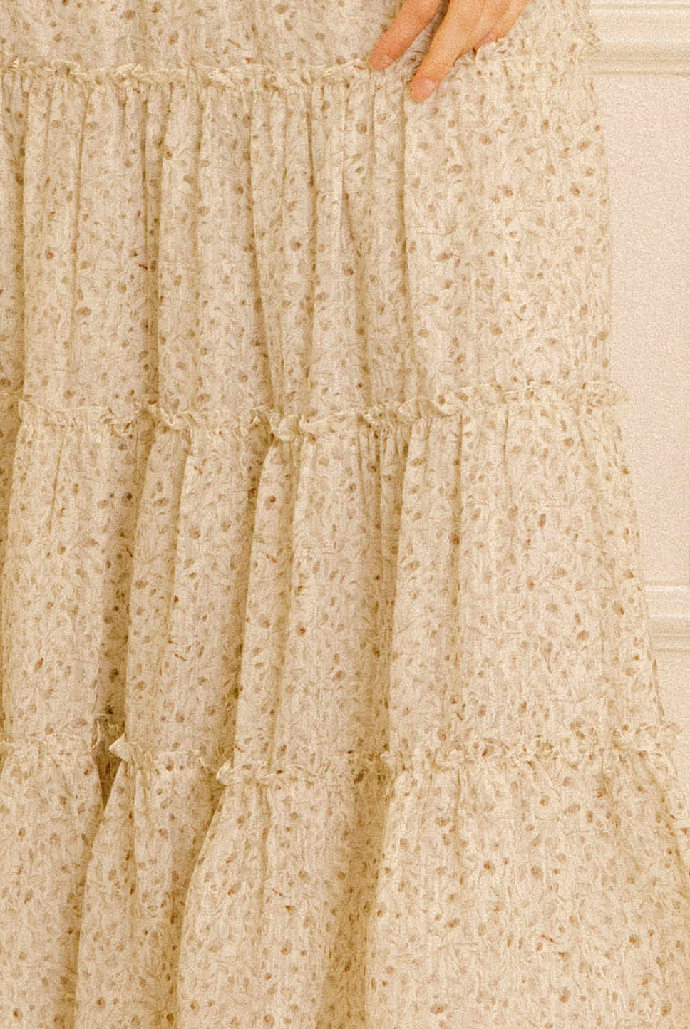 Details of a grey floral dress against a cream wall