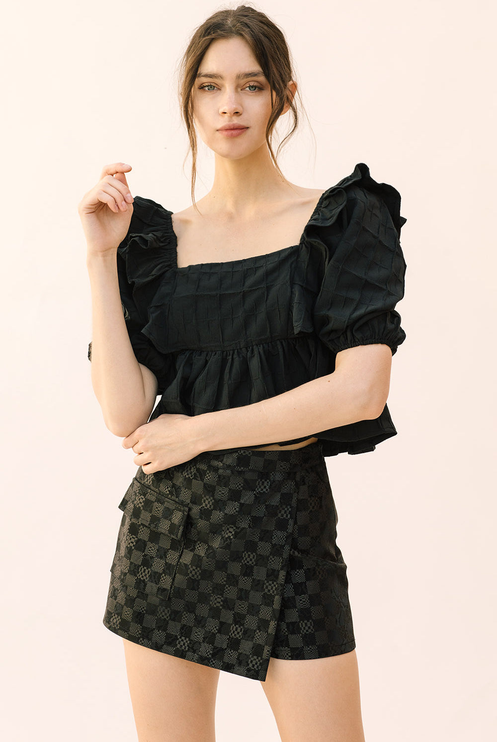 Woman wearing a black top and patterned shorts on a beige background