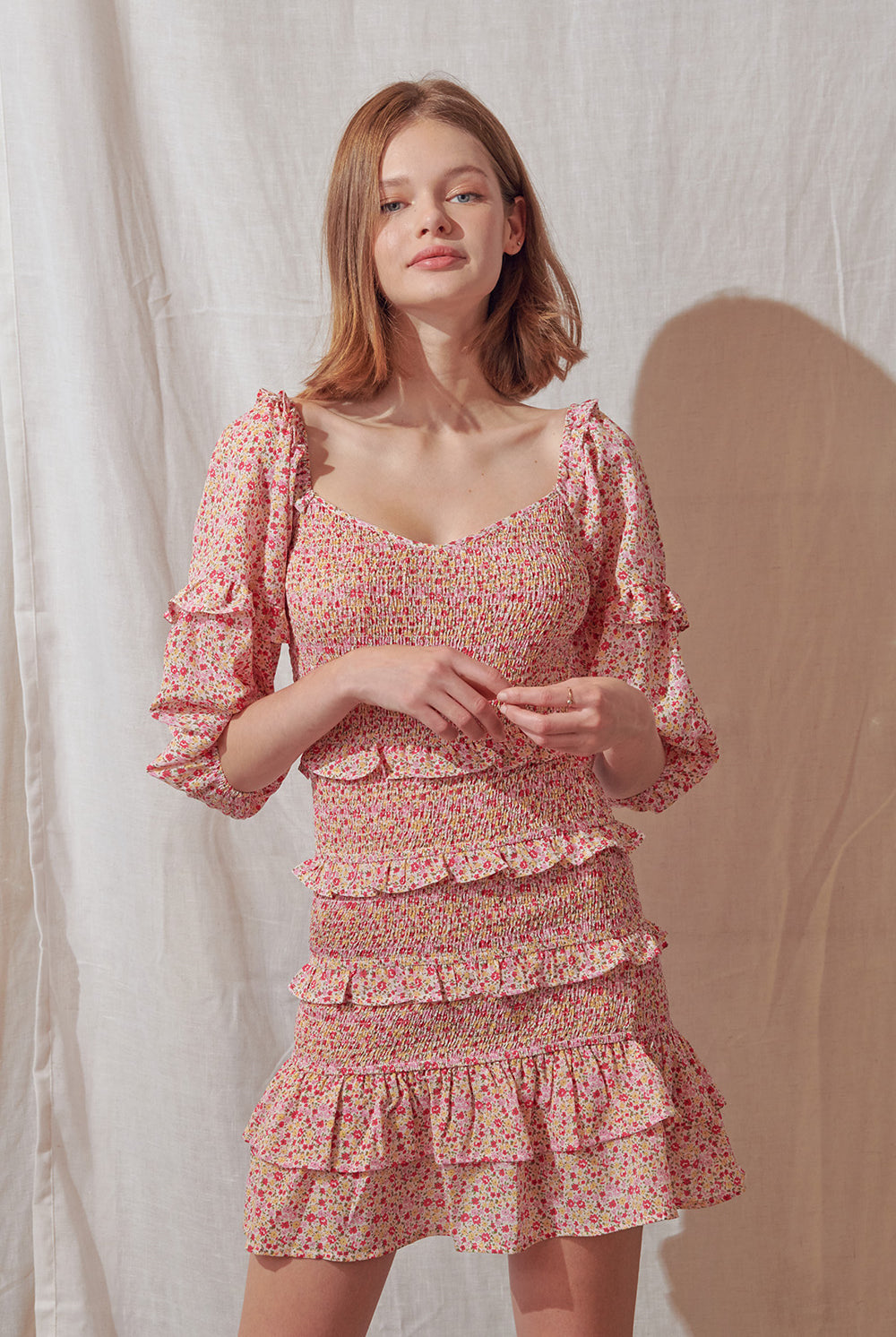Woman wearing a pink floral dress against a plain background