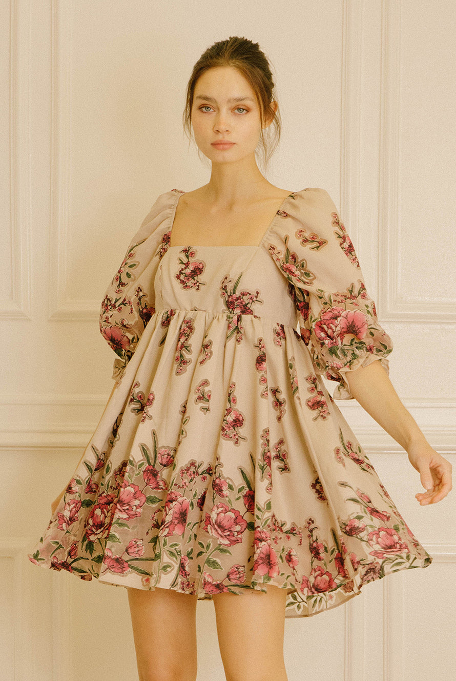 Woman wearing a floral dress against a neutral background