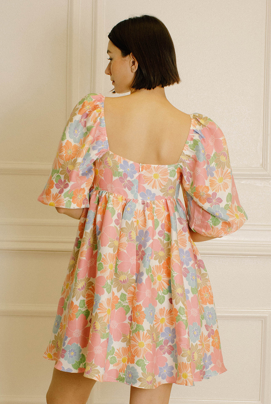 Back view of a woman wearing a floral dress against a neutral background