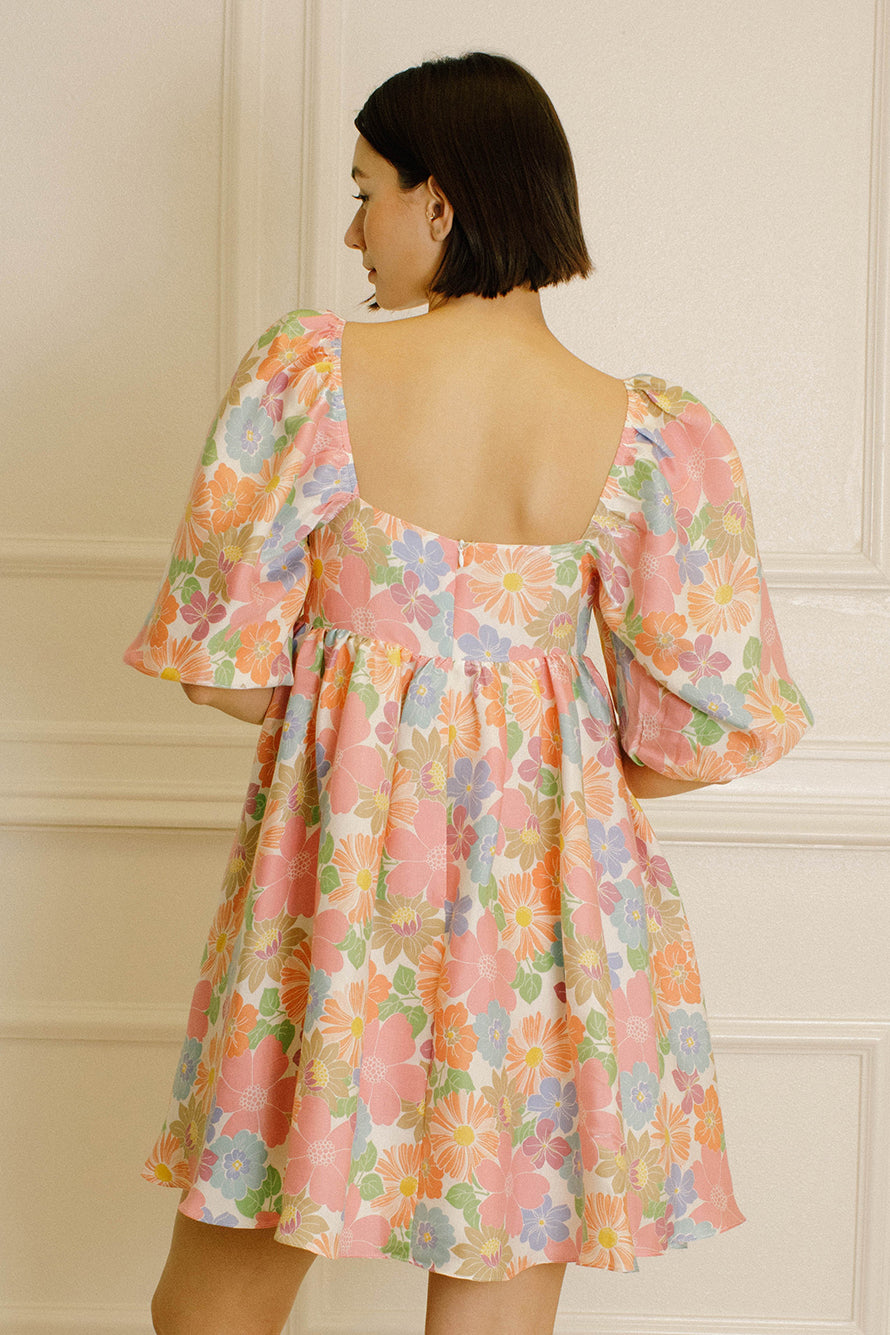 Back view of a woman wearing a floral dress against a neutral background