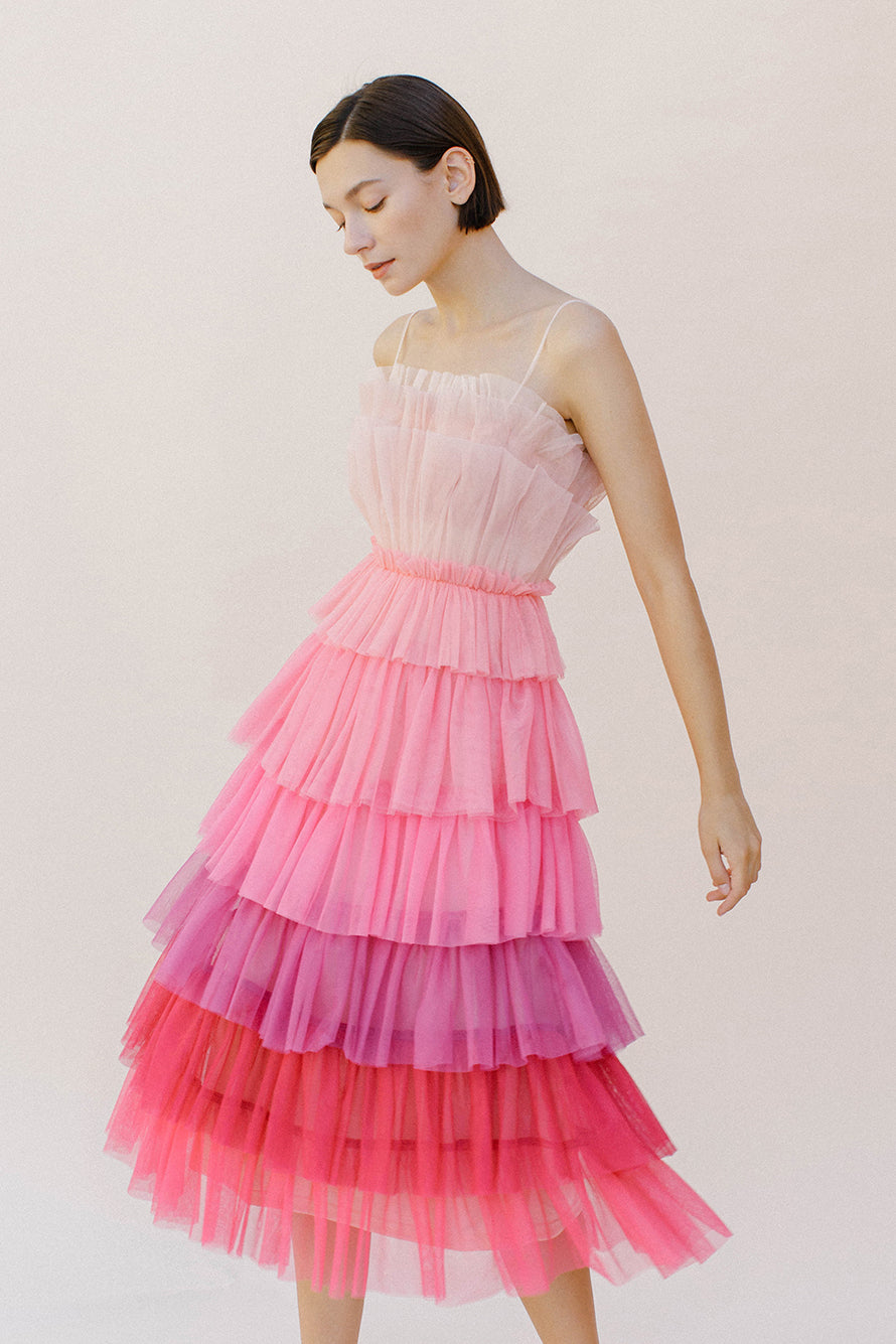 Woman wearing a pink ombre tulle tiered dress against a white background