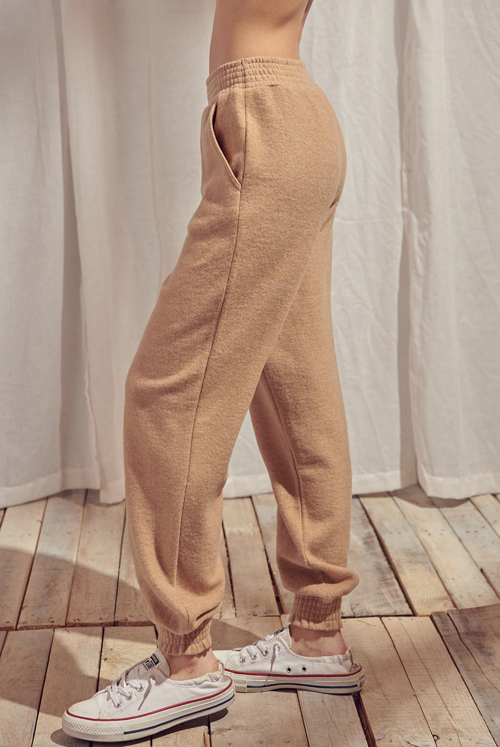 Side view of beige pants standing against a white curtain.