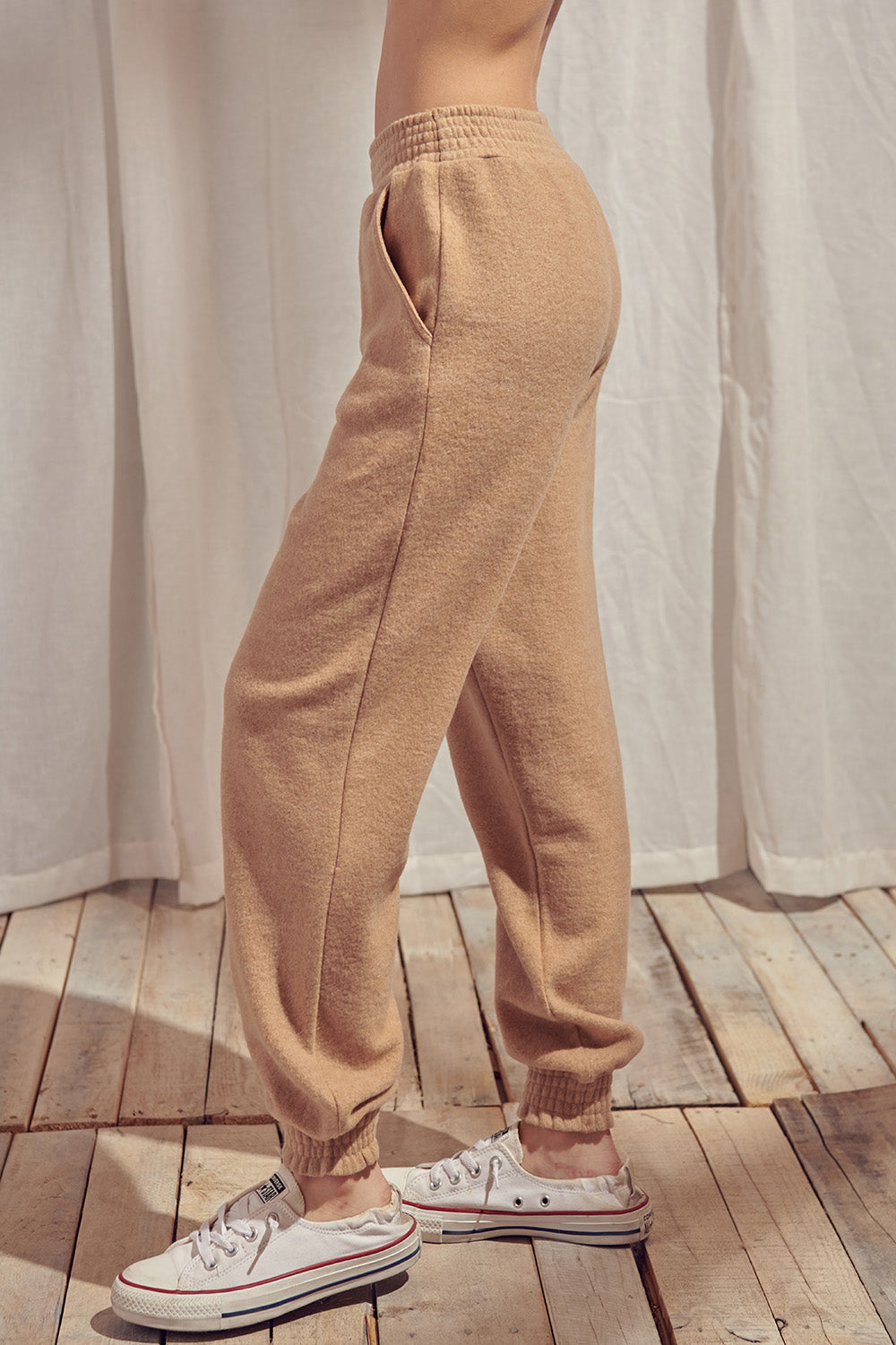 Side view of beige pants standing against a white curtain.