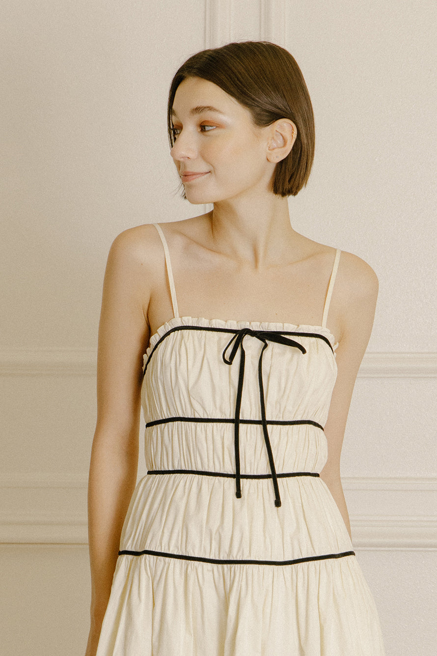 Woman wearing a cream dress with black trim