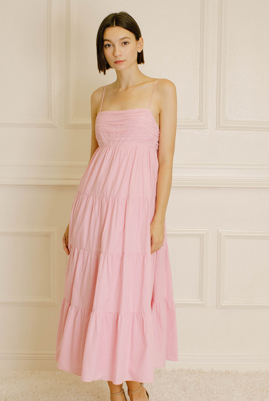 Woman wearing a pink tiered dress on a white background