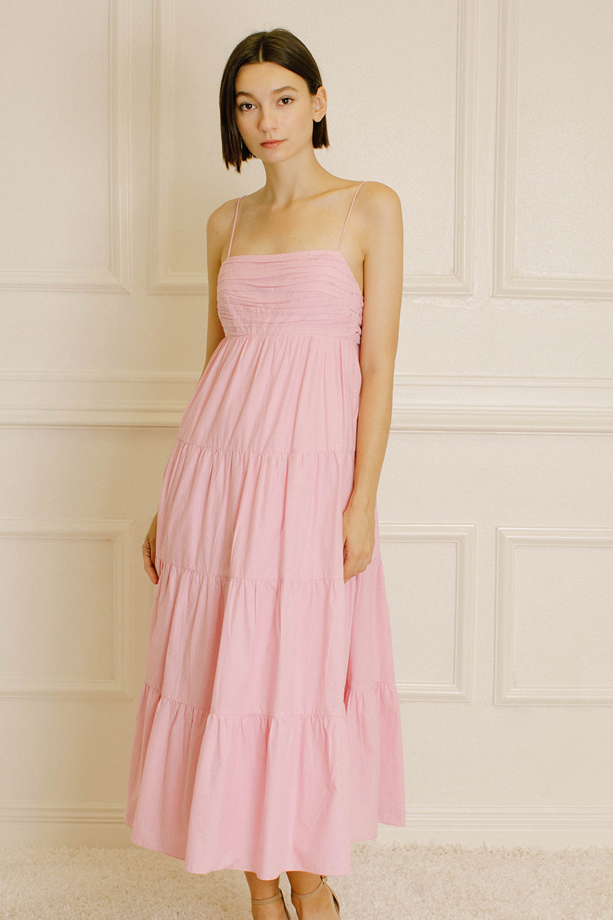 Woman wearing a pink tiered dress on a white background