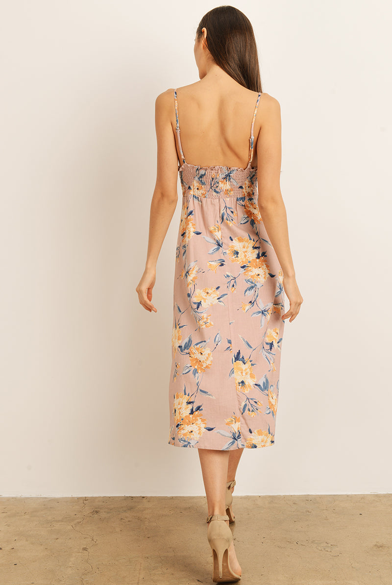 Back view of a woman wearing a mauve floral dress on a plain background