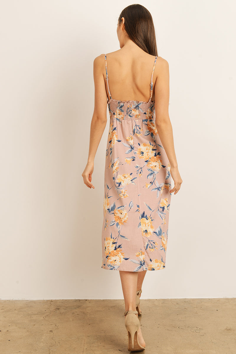 Back view of a woman wearing a mauve floral dress on a plain background