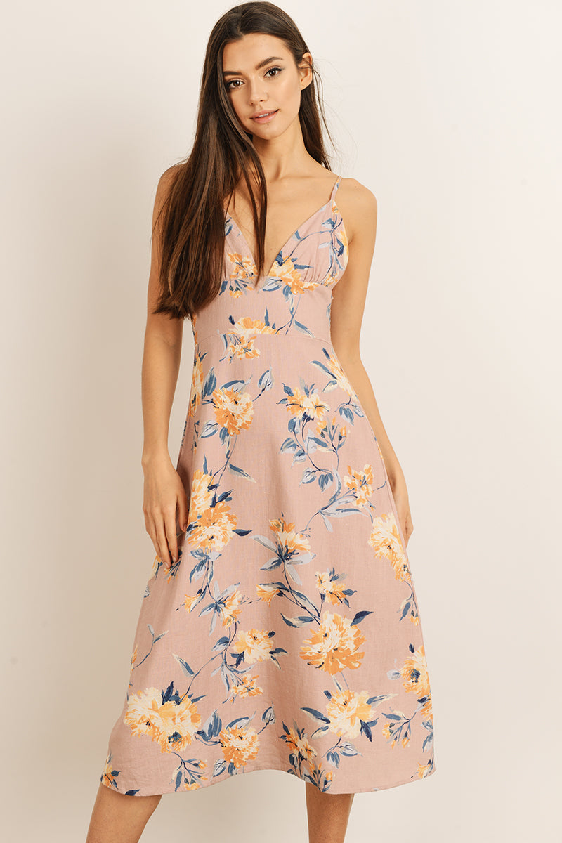 Woman wearing a mauve floral dress on a plain background