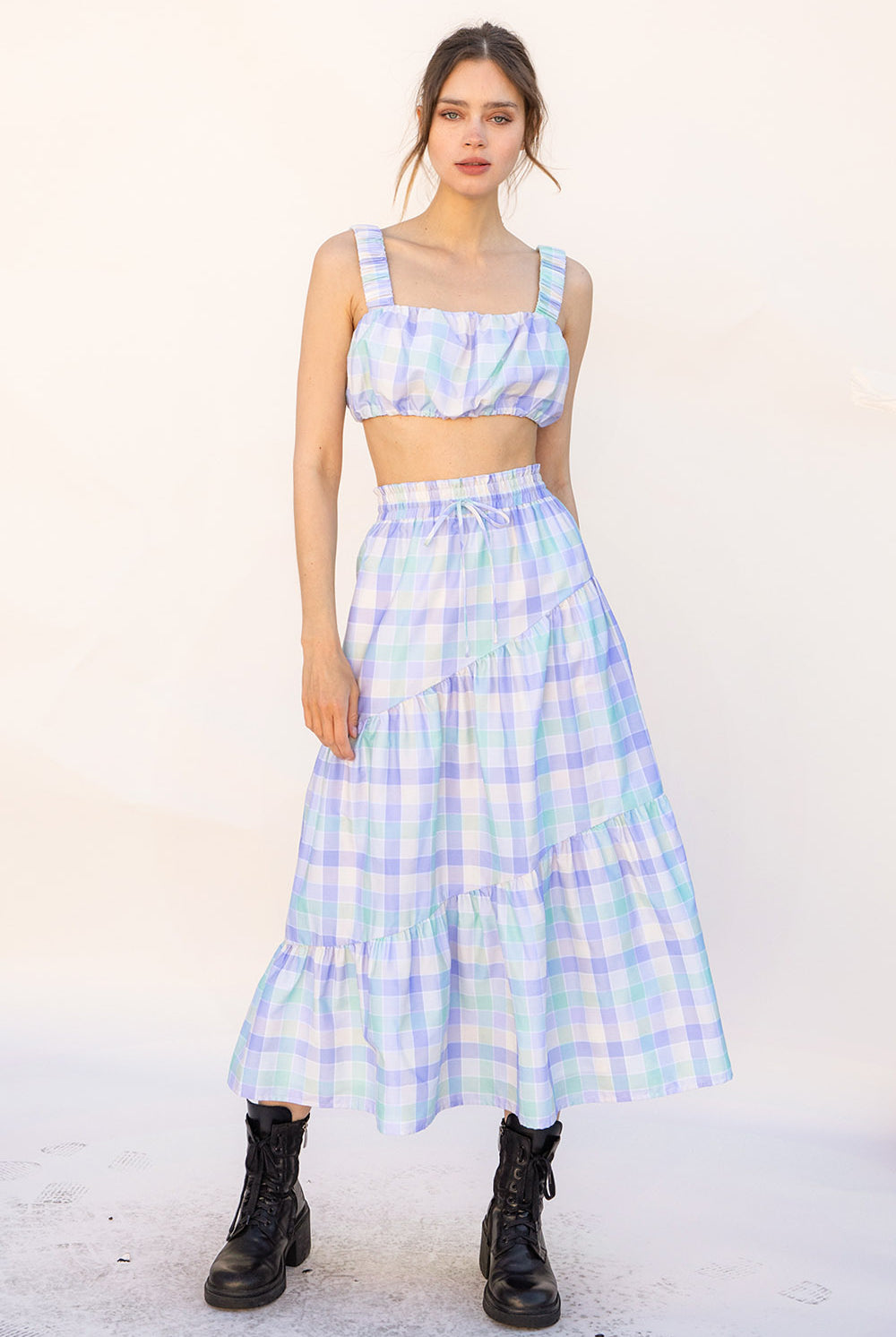 Woman wearing a pastel plaid top and skirt set with a white background