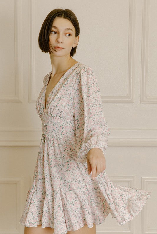 Woman wearing a pink dress with a cinched waist and a floral pattern against a neutral background