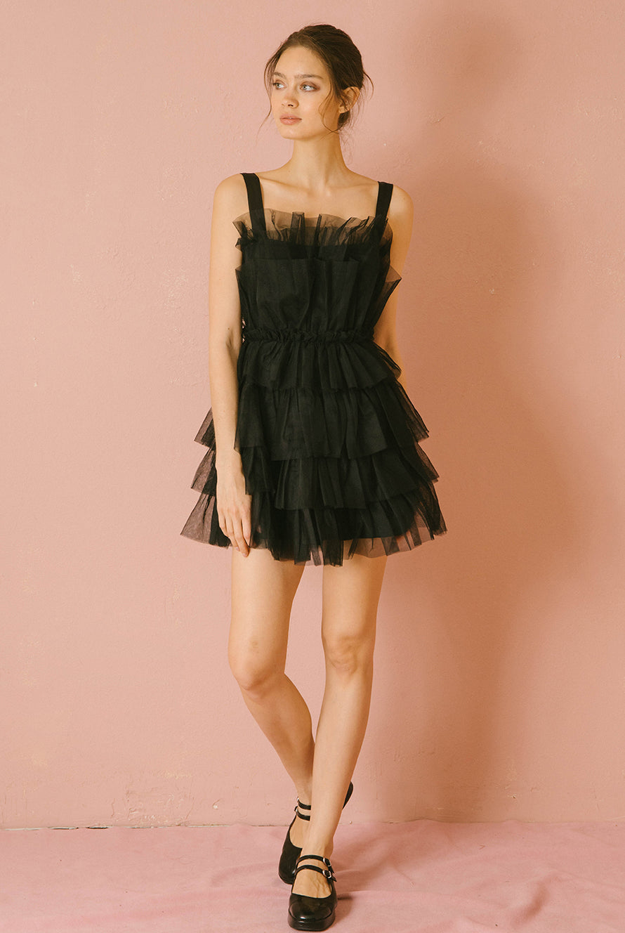 Woman wearing a black tulle dress against a pink background