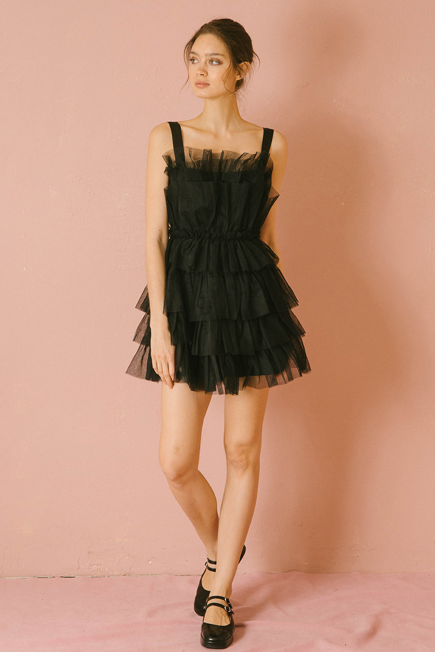 Woman wearing a black tulle dress against a pink background