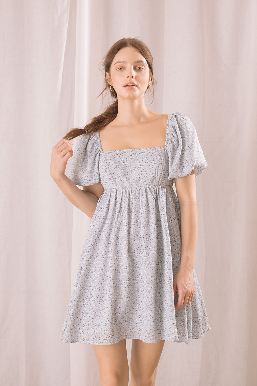Woman wearing a light blue floral dress against a plain background