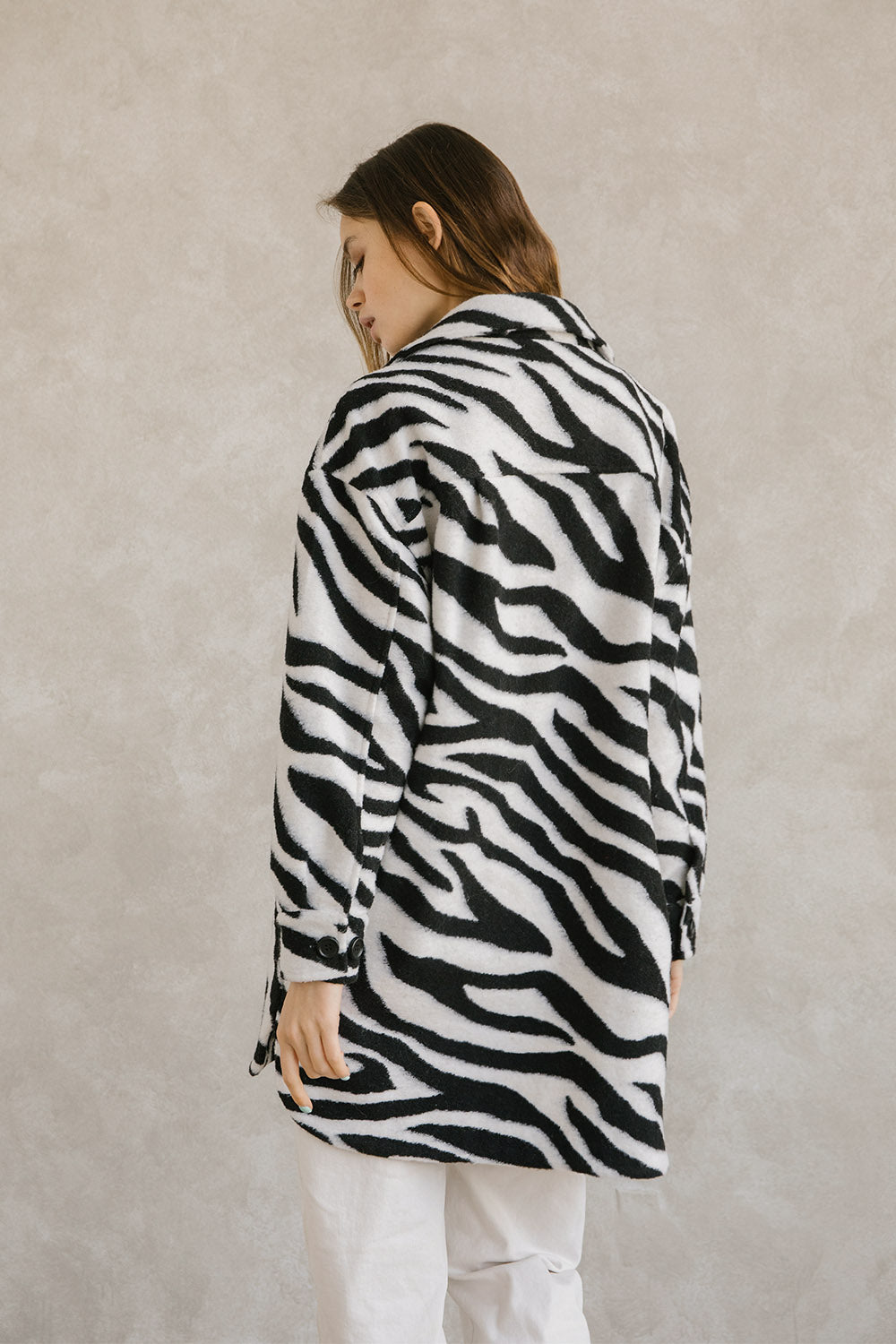 Back view of a woman wearing a zebra-patterned coat against a plain background