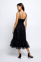 Woman wearing a black lace dress and black high-heels on a white background
