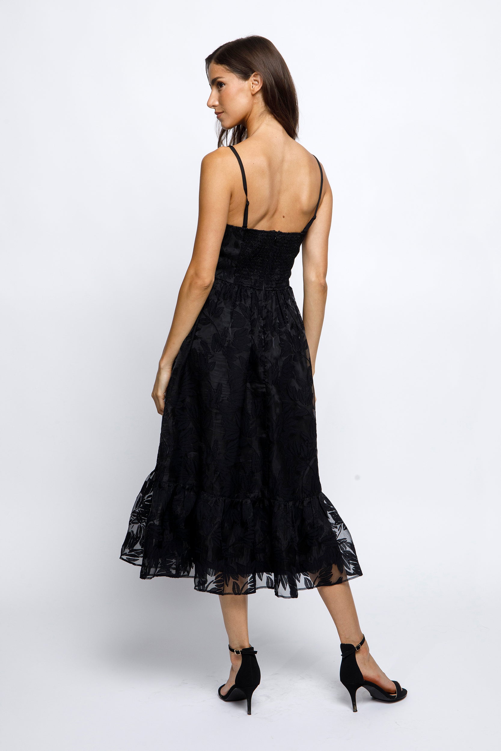 Woman wearing a black lace dress and black high-heels on a white background
