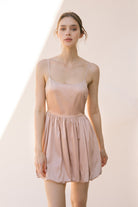 Woman wearing a sheer beige dress against a plain background