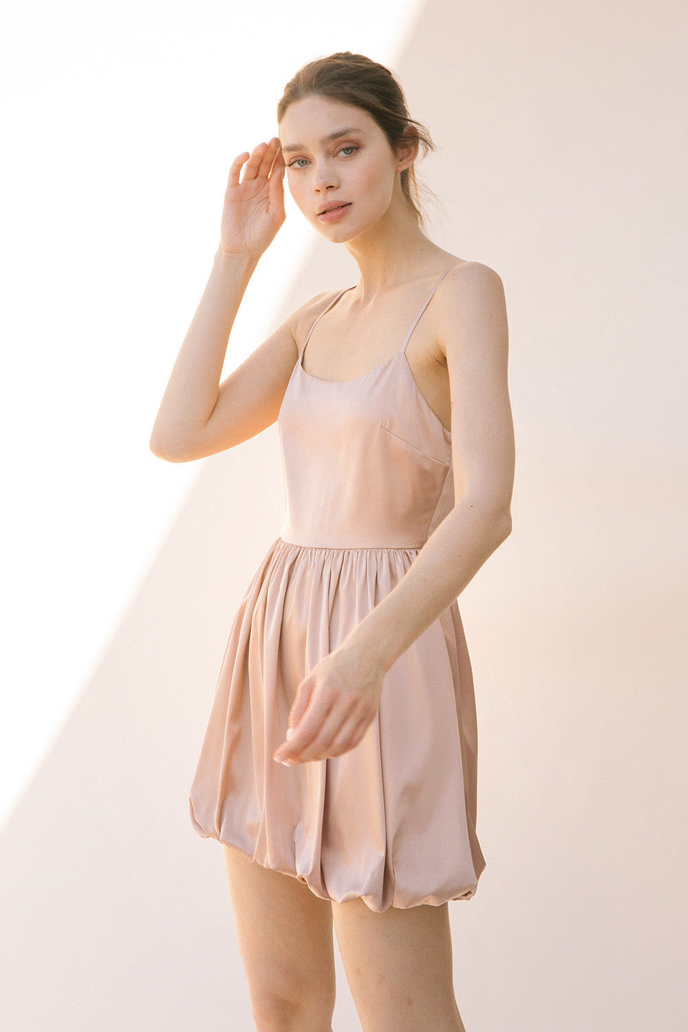 Side view of a woman wearing a sheer beige dress against a plain background
