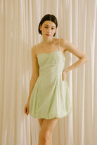 Woman wearing a mint polka dot mini dress against a white background