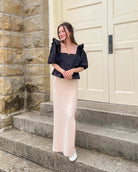 Woman wearing a black blouse standing on steps in front of a large door.